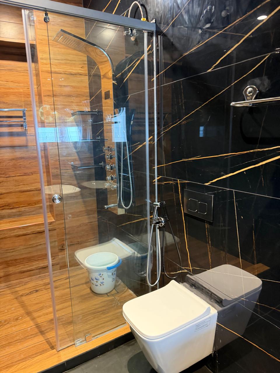 Luxury bathroom with glass shower box and gold veined black marble